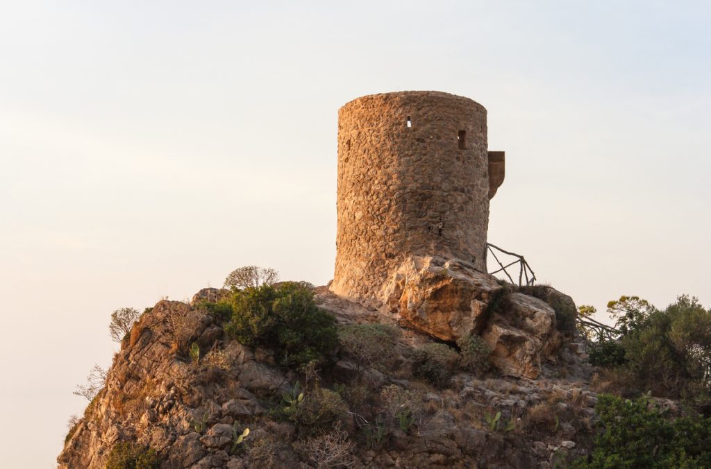 Historischer Rundturm auf Felsklippe bei Banyalbufar im warmen Abendlicht.