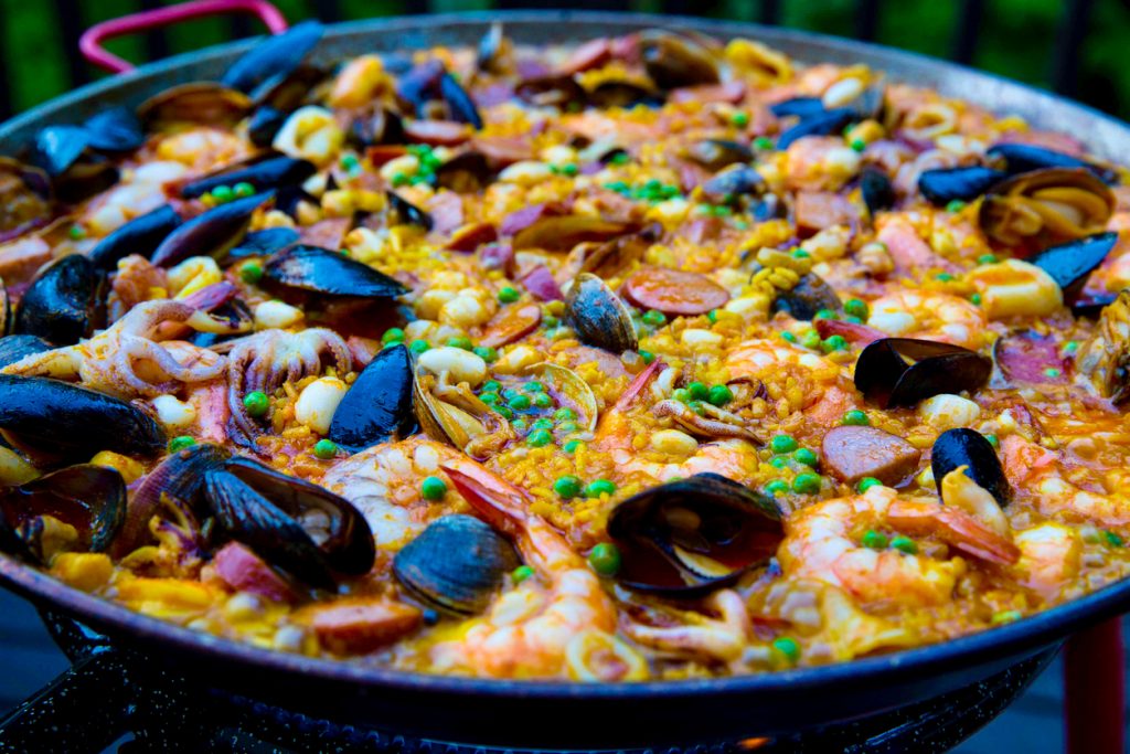Nahaufnahme einer Paella mit Muscheln, Garnelen, Tintenfisch, Erbsen und Chorizo.