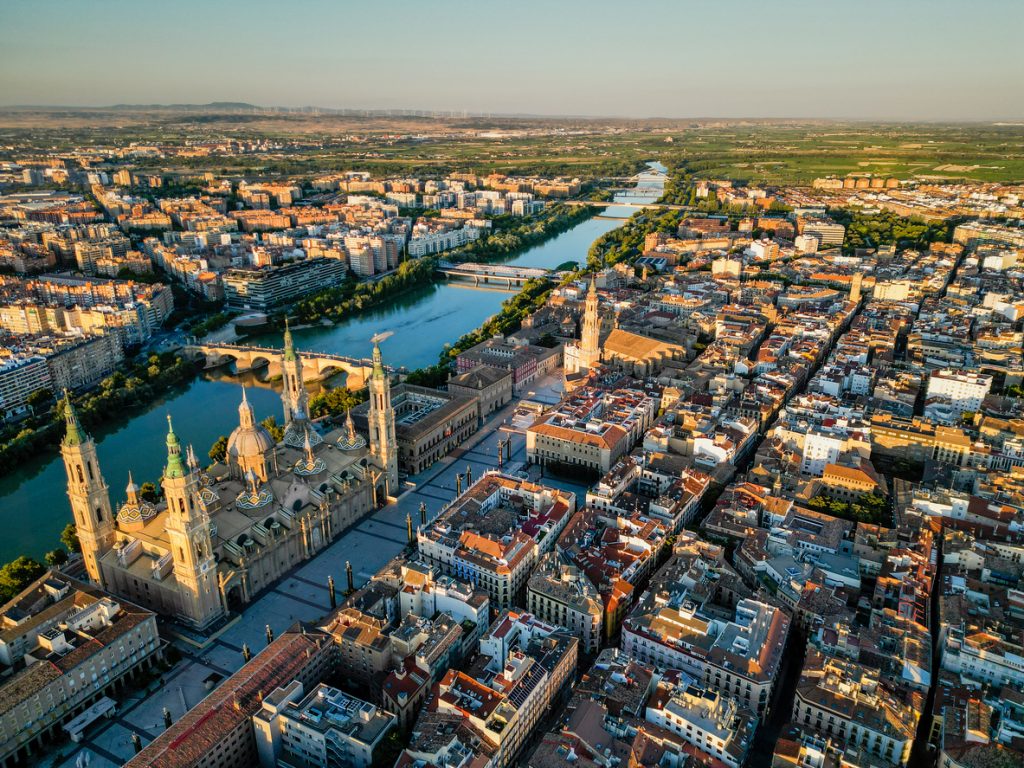 Die Basílica del Pilar, die Altstadt und der Ebro liegen im warmen Abendlicht aus der Vogelperspektive.