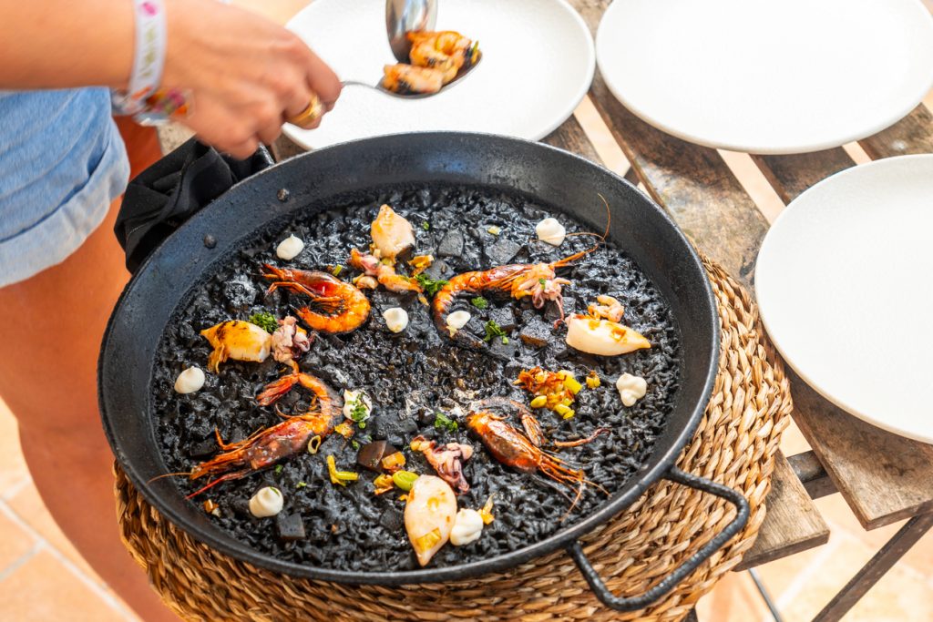 Schwarze Tintenfisch-Paella mit Garnelen und Calamari in der Pfanne.