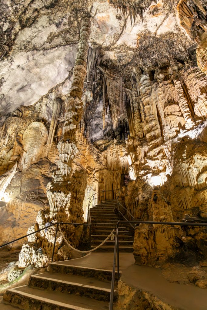 Beleuchtete Tropfsteinhöhle mit steiler Treppe und vielen Stalaktiten in den Coves d’Artà, Mallorca.