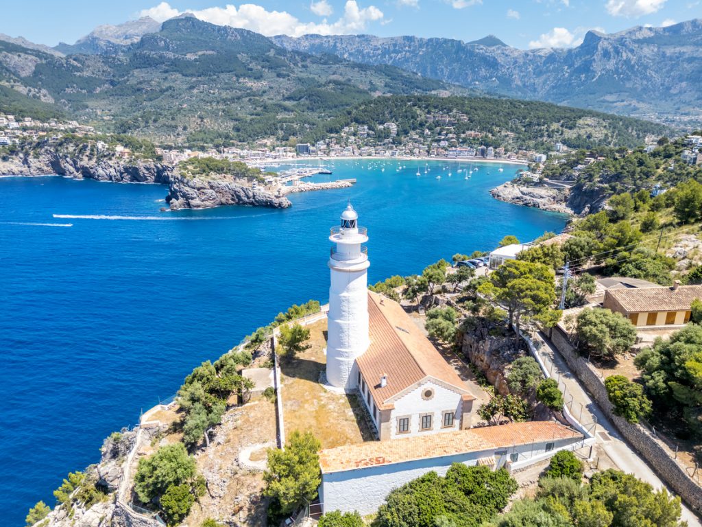 Luftaufnahme des weißen Leuchtturms Far del Cap Gros auf einer Klippe mit Blick über die Bucht von Port de Sóller und die Tramuntana.