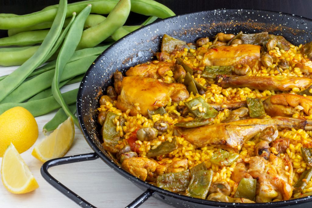 Traditionelle Paella Valenciana mit Huhn, Kaninchen, grünen Bohnen und Garrofón in einer Paellapfanne.