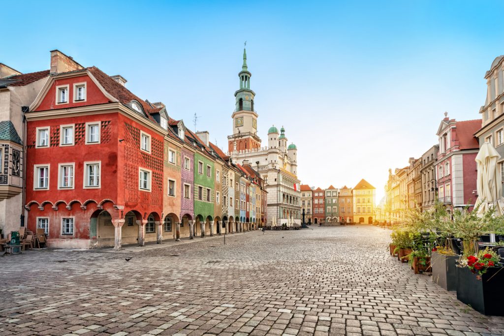 Farbige Giebelhäuser und das historische Rathaus am Stary Rynek in Poznań bei Sonnenaufgang.