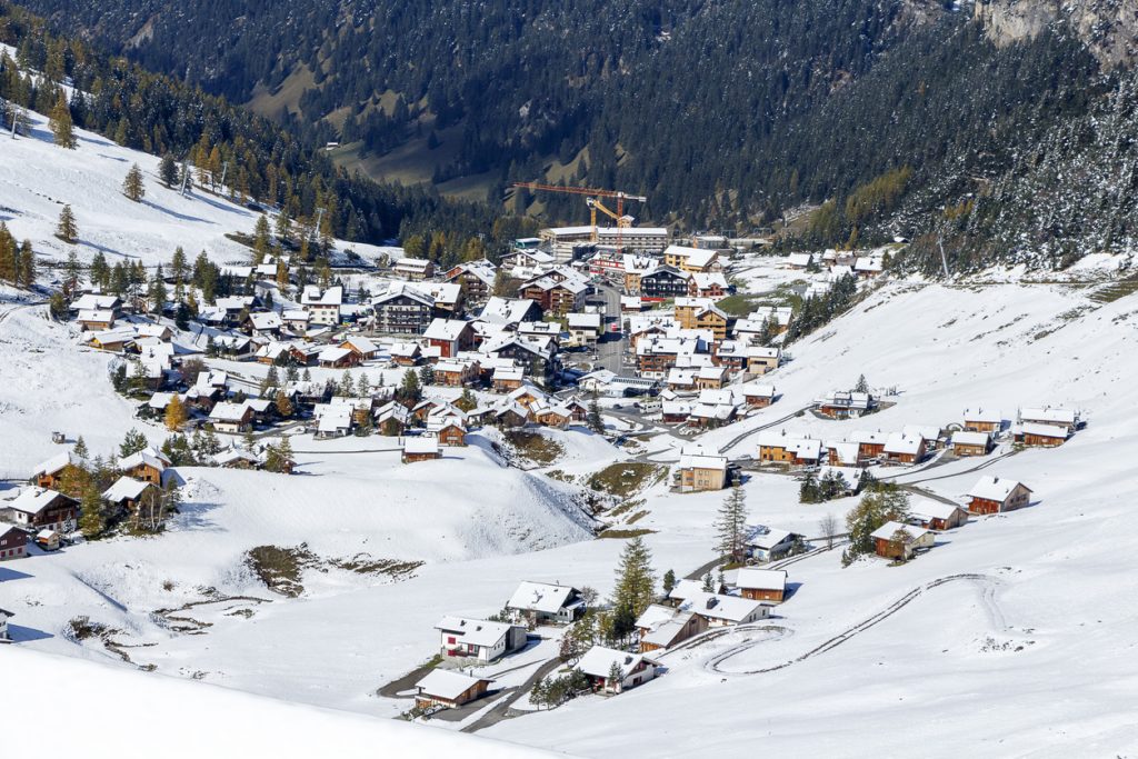 Schneebedecktes Bergdorf Malbun mit Chalets und Straßen im alpinen Hochtal.