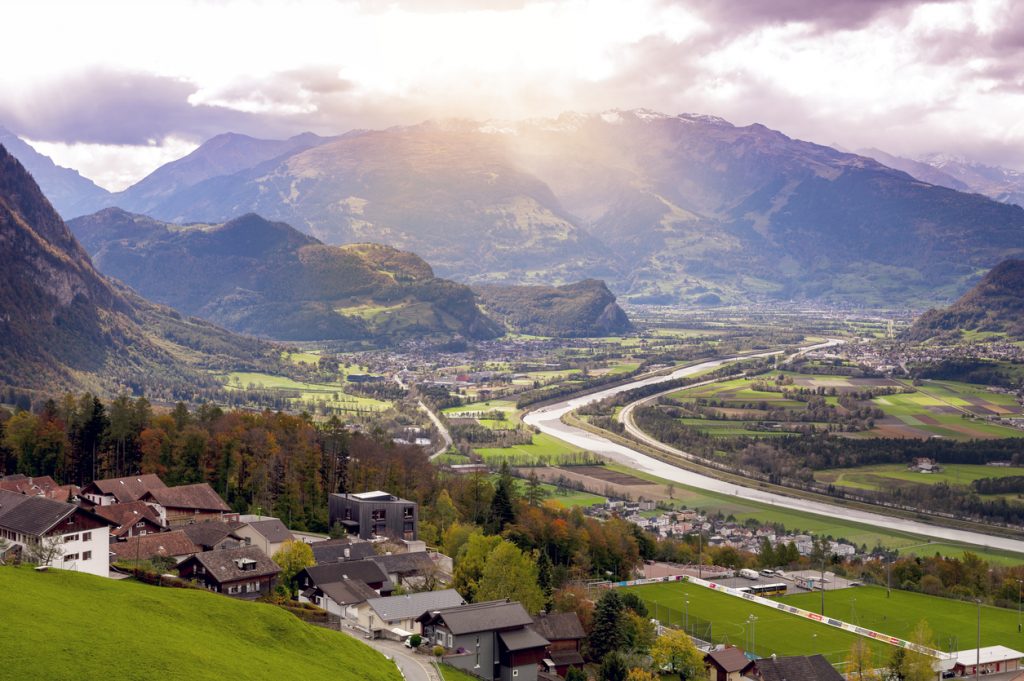 Panoramablick über ein Bergtal mit Fluss, Feldern und verstreuten Dörfern.