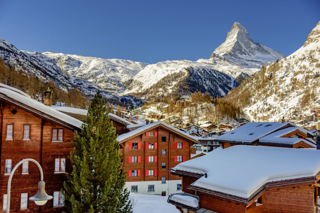 Holzchalets von Zermatt vor verschneiten Hängen und dem markanten Matterhorn.