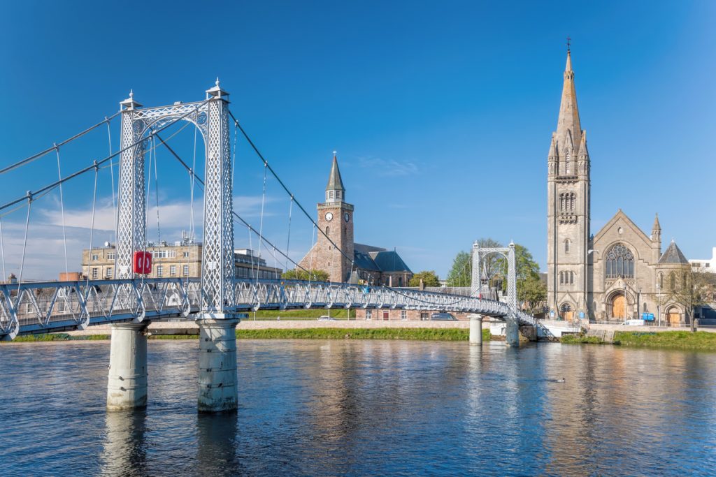 Helle Hängebrücke über den River Ness mit zwei Kirchtürmen im Zentrum von Inverness.