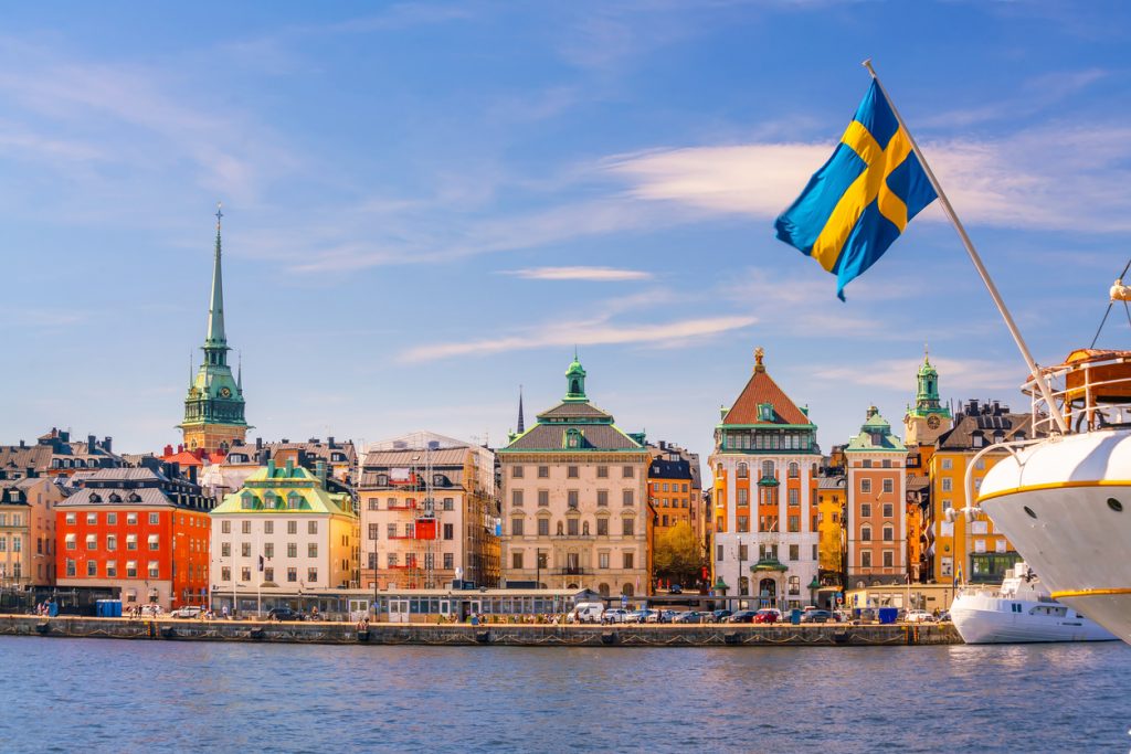 Schwedische Flagge vor den historischen Fassaden an der Uferpromenade.