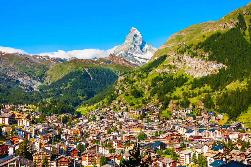 Blick auf Zermatt vor grünen Alpenhängen und dem Matterhorn.