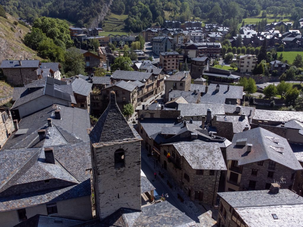 Luftaufnahme mit engen Gassen, grauen Schieferdächern und Kirchturm im Dorf Ordino.