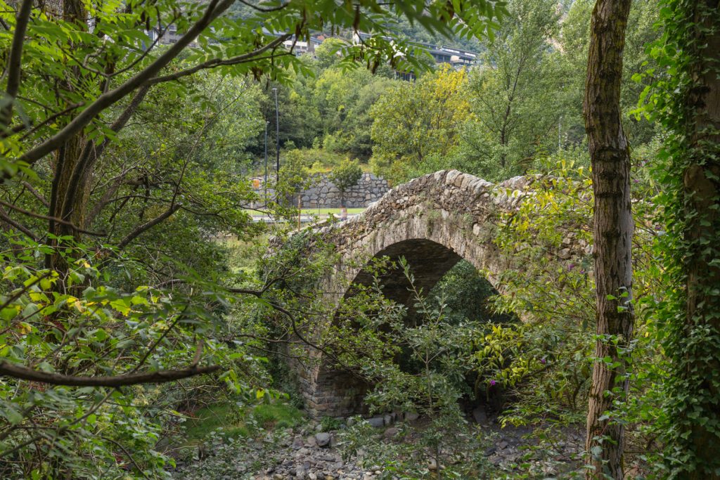 Alte Steinbrücke über einem Bachbett im Wald von Andorra la Vella.