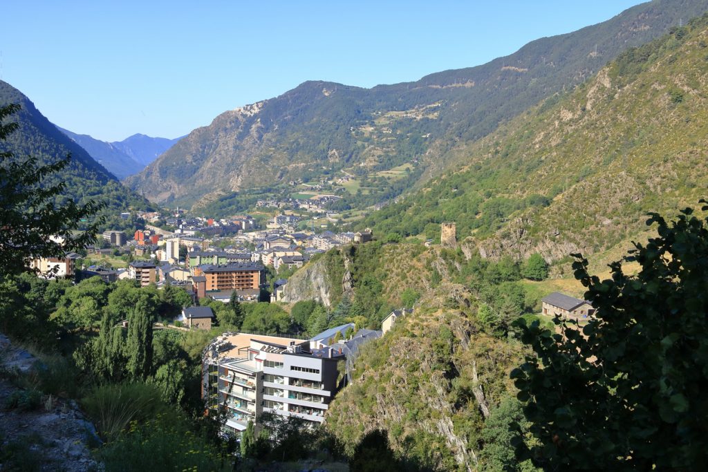 Panorama von Encamp in einem grünen Bergtal mit Häusern und einer kleinen Turmruine.