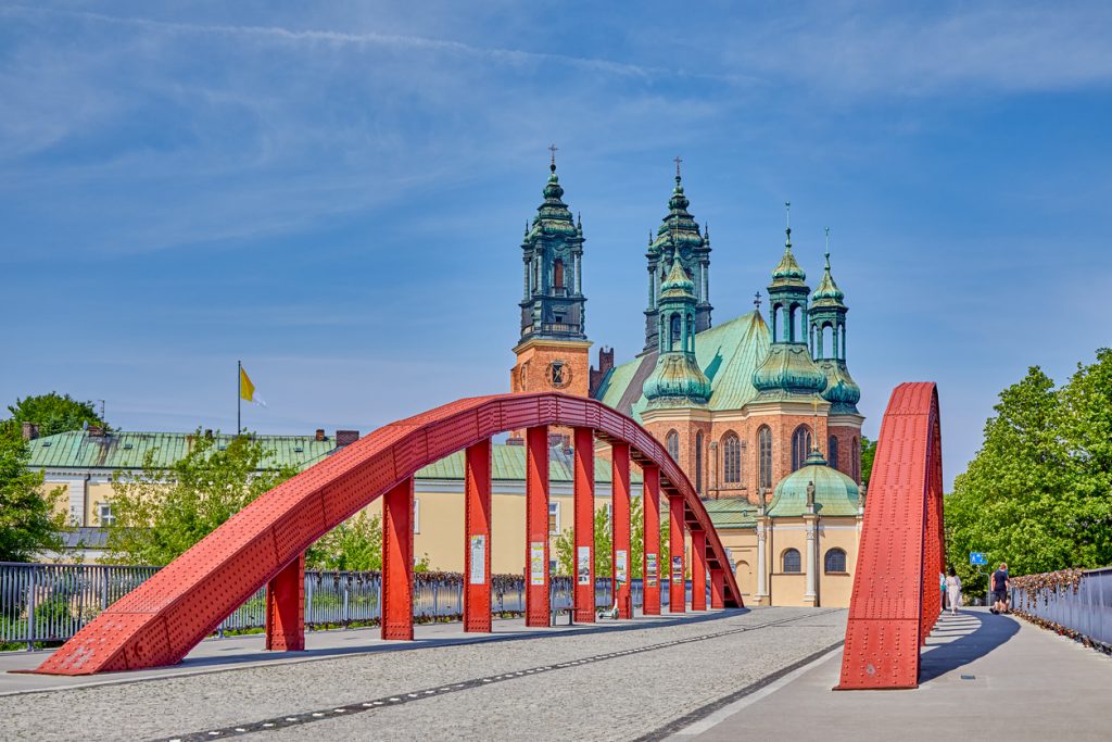 Stählerne Bogenbrücke führt zur Kathedrale von Poznań bei klarem Himmel.