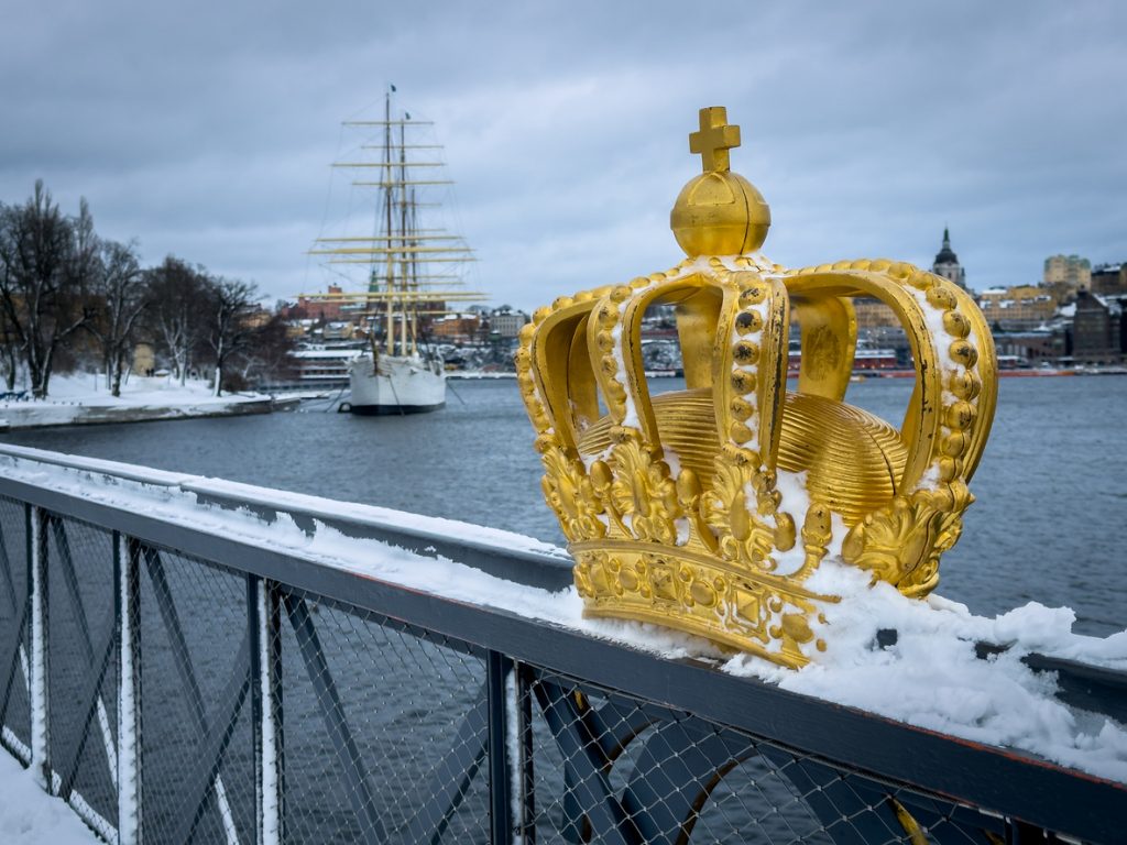 Vergoldete Krone auf der Brücke mit verschneitem Geländer und Segelschiff.