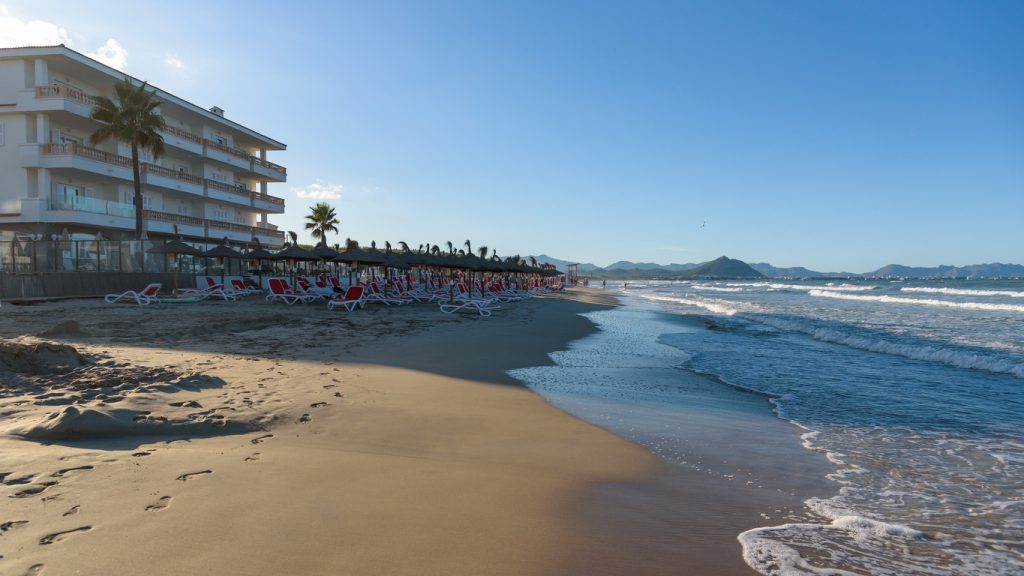 Breiter Sandstrand mit Liegen vor einem Hotel zwischen Can Picafort und Alcudia.