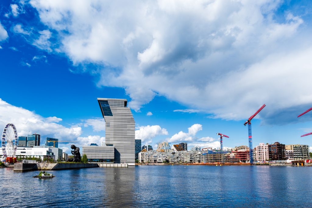 Schräger MUNCH-Bau und Barcode-Skyline am Oslofjord mit Kranen und Riesenrad.