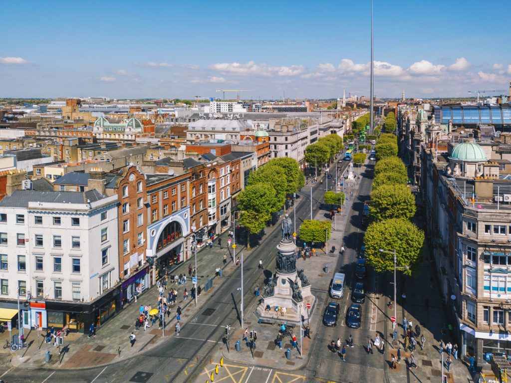 Luftbild der O’Connell Street mit dem Spire, Baumreihen und geschäftigem Stadtverkehr.
