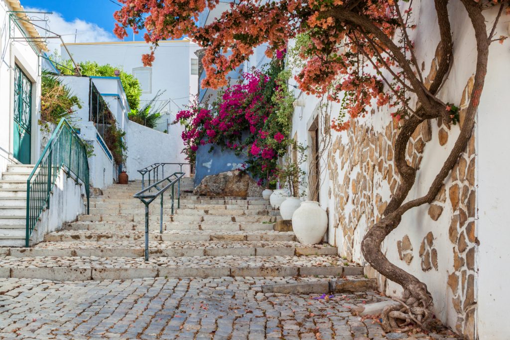 Gasse mit Treppen, Bougainvillea und weißen Häusern in der Cidade Velha.