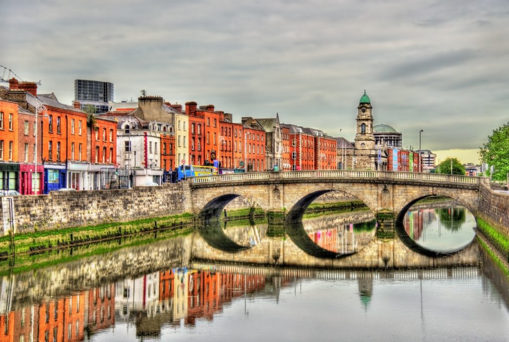 Historische Steinbrücke und Ziegelhäuser spiegeln sich im ruhigen River Liffey in Dublin.
