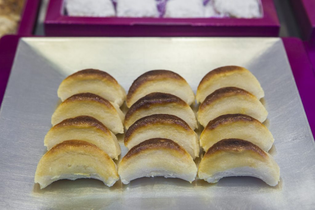 In Reihen angeordnete, halbmondförmige Marzipanstücke aus Toledo auf einem Metalltablett.