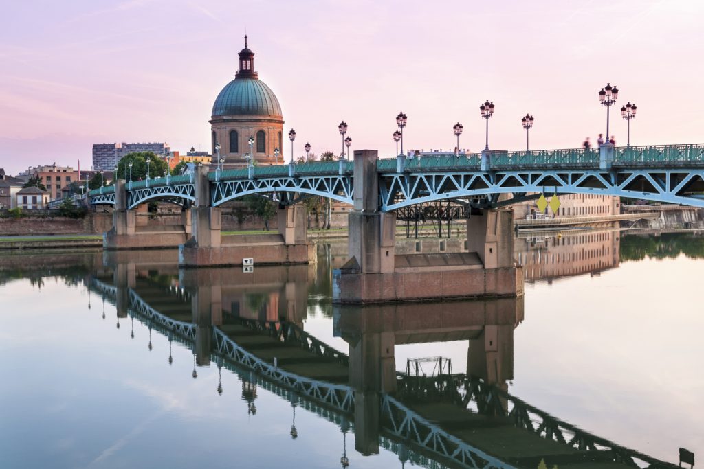 Brücke über der Garonne vor der grünen Kuppel im Abendlicht.