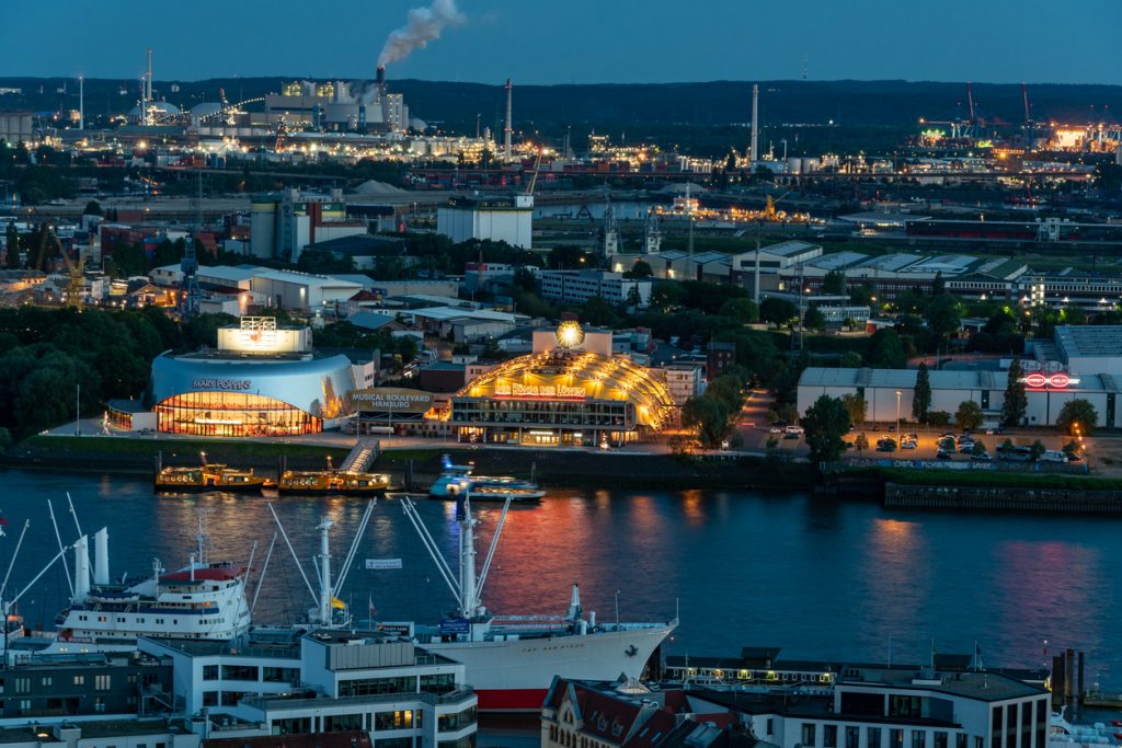 Zwei Musicaltheater leuchten am Abend am Hamburger Hafen.