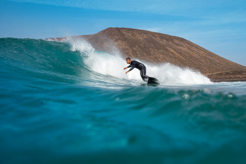 Surfer im Neopren gleitet auf einer hohen Welle vor der Küste von Fuerteventura.