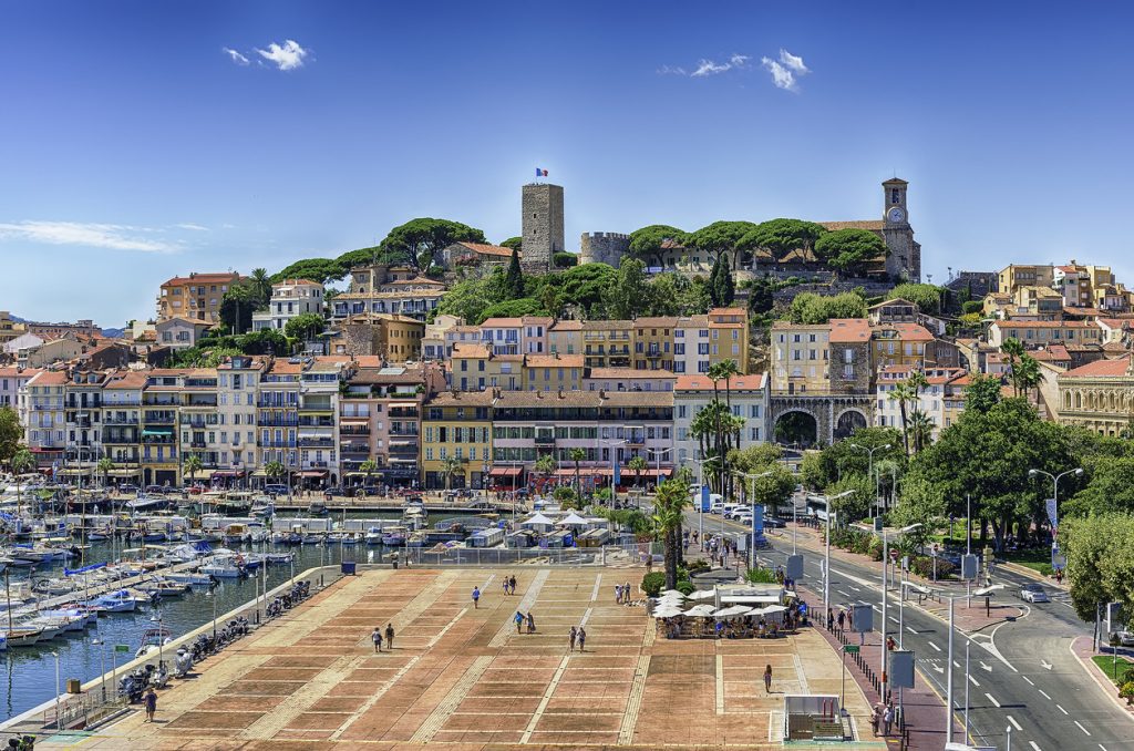 Blick auf bunte Häuser, Yachthafen und Altstadt in einer Küstenstadt an der Côte d’Azur.