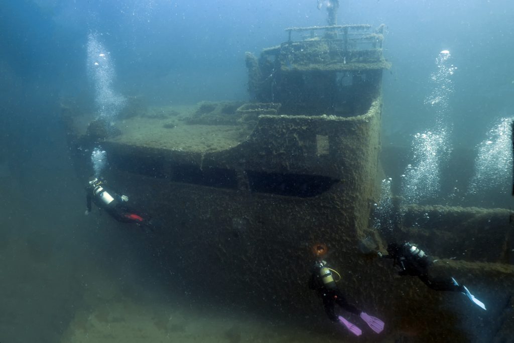 Taucher erkunden ein versunkenes Schiffswrack auf dem Meeresboden beim Tauchen auf Mallorca.
