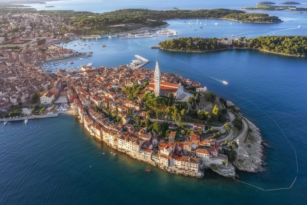 Luftaufnahme von Rovinj mit Altstadt, Kirchturm und blauem Meer rund um die Halbinsel in Kroatien.