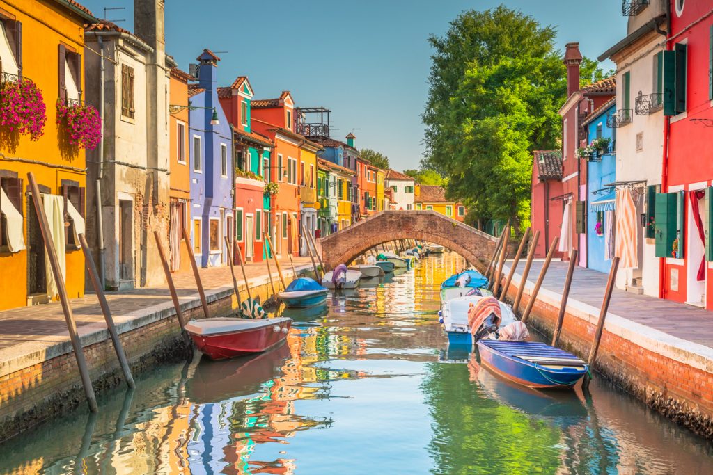 Kanal mit Booten und leuchtend bunten Häusern auf der Insel Burano bei Venedig.