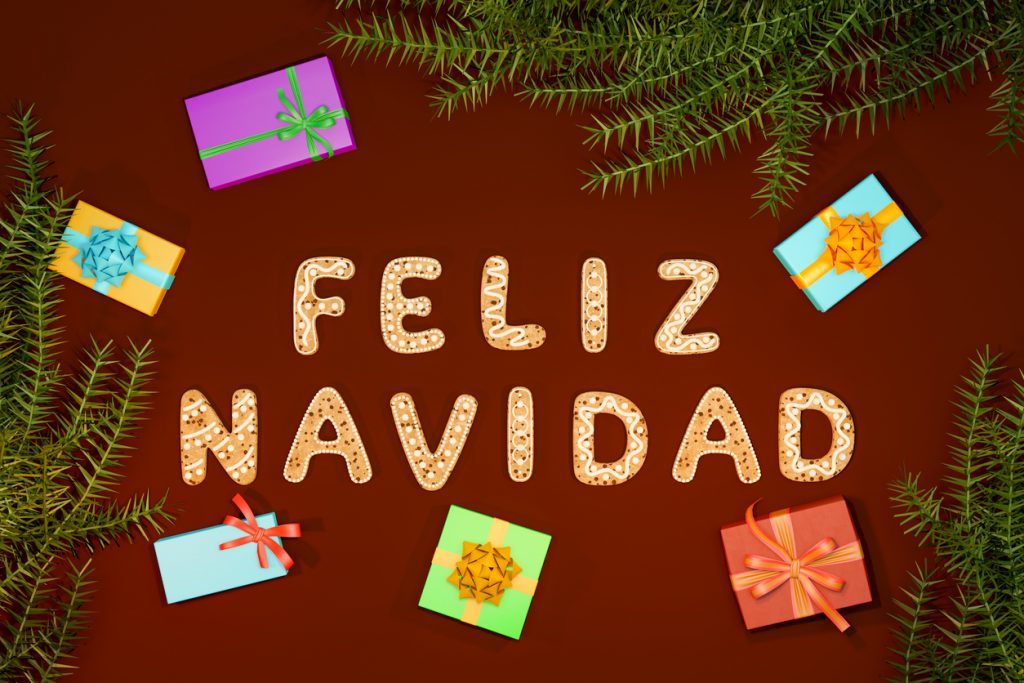 Schriftzug „Feliz Navidad“ aus Keksbuchstaben mit bunten Geschenken und Tannenzweigen, der eine mögliche El-Gordo-Gewinnweihnacht symbolisiert.