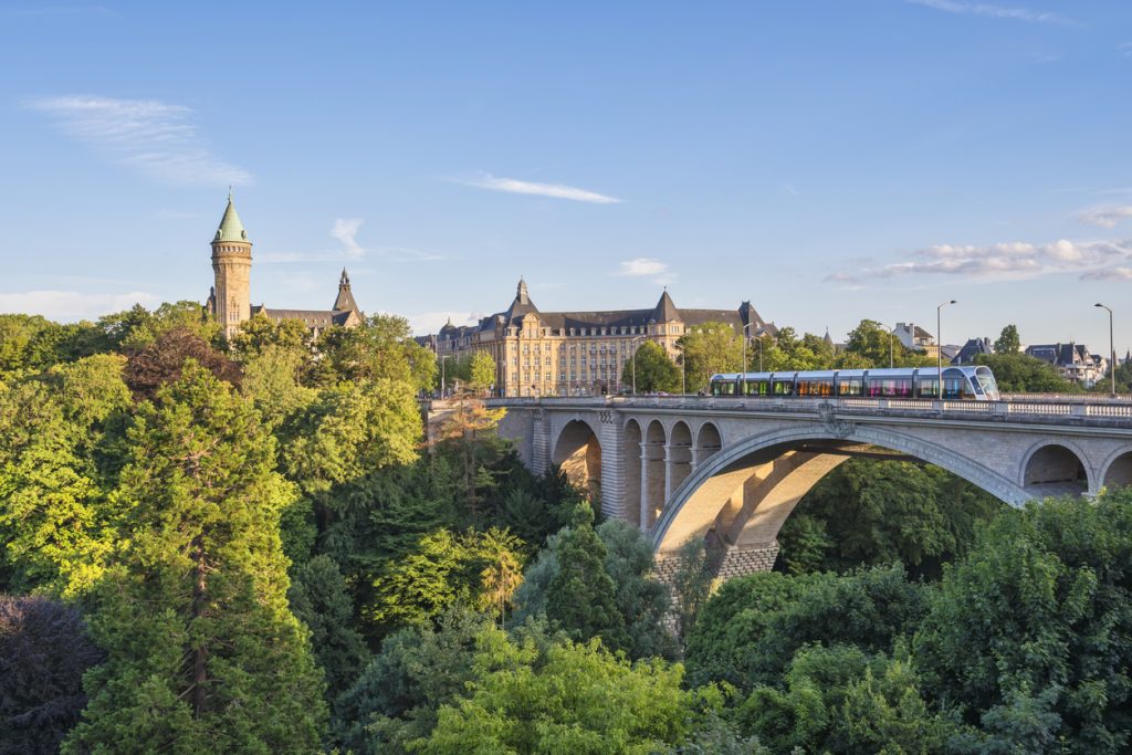 Pont Adolphe in Luxemburg Stadt mit Tram auf der Brücke und Blick ins bewaldete Tal.