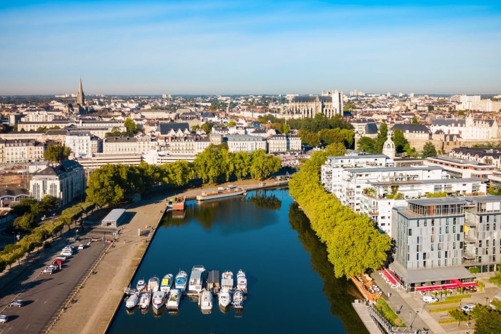Von oben sieht man in Nantes Boote am Ufer, eine Baumallee und die Stadt bis zum Horizont.