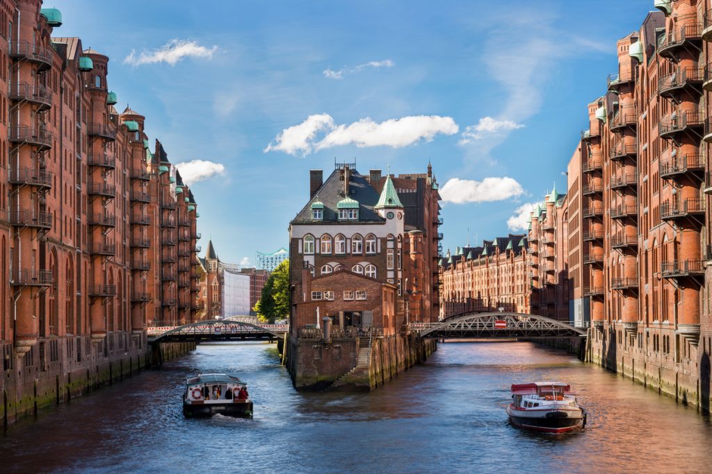 Ein Kanal in der Hamburger Speicherstadt führt zwischen Backsteinlagern in die Stadt.