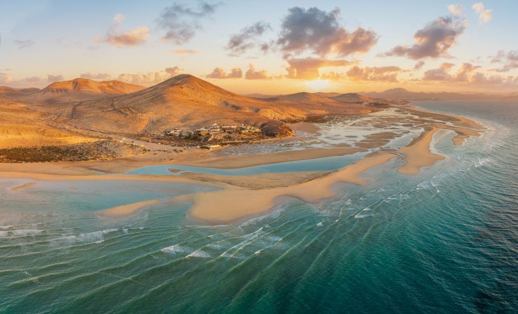 Luftaufnahme von hellen Sandbänken und flachen Lagunen an der Küste von Fuerteventura.