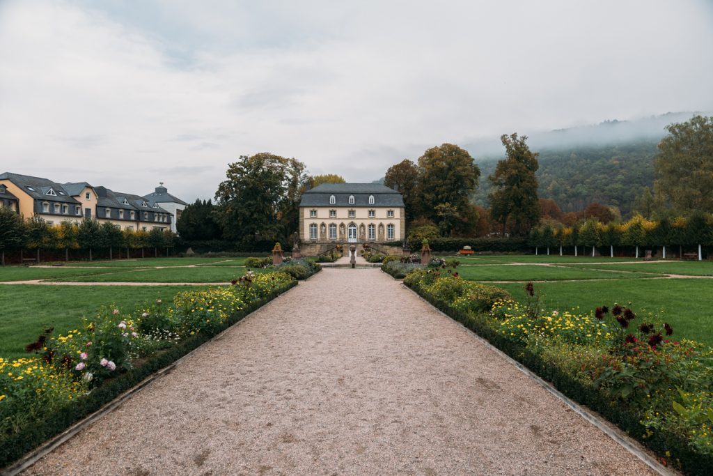 Gerade Gartenachse mit Blumenbeeten und einem Herrenhaus in einer Parkanlage in Luxemburg.