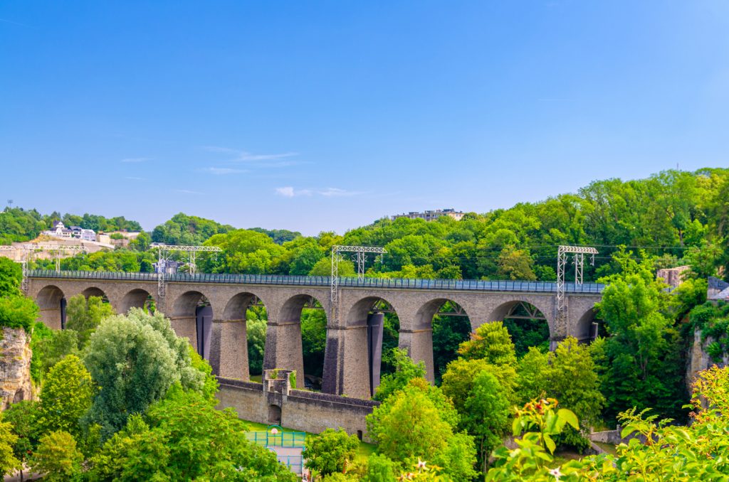 Steinviadukt mit vielen Bögen über einem bewaldeten Tal in Luxemburg.