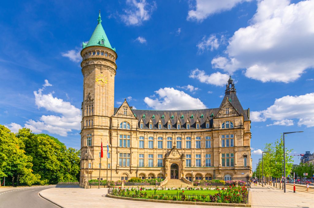 Rathaus von Luxemburg Stadt mit hohem Turm, Uhr und historischer Fassade bei blauem Himmel.