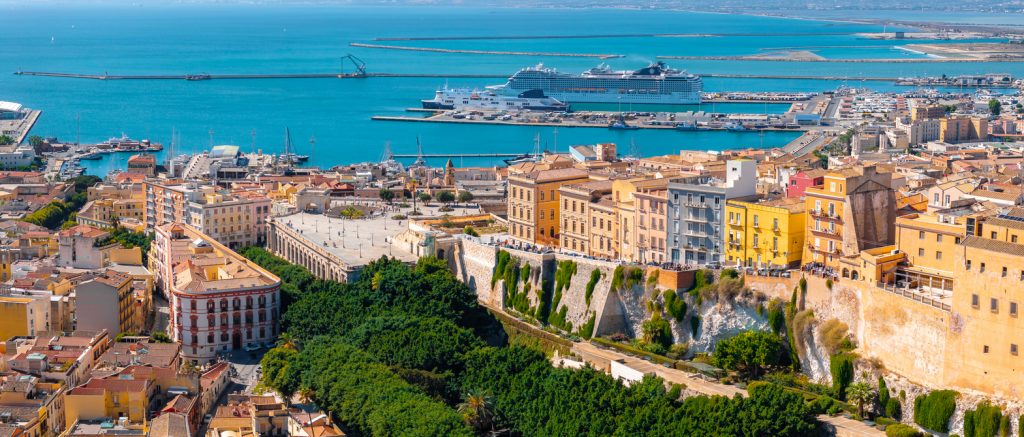 Luftaufnahme von Cagliari mit Hafen, Kreuzfahrtschiffen und historischen Häusern.