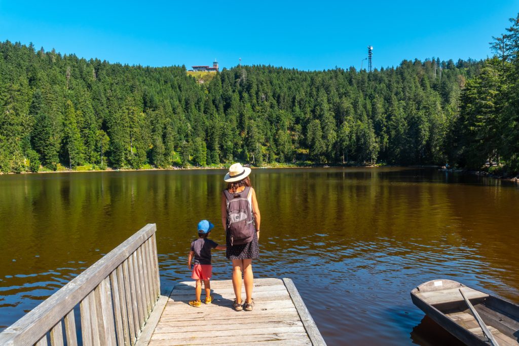 Mutter und Kind stehen auf einem Steg an einem stillen Schwarzwaldsee.