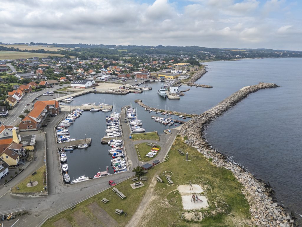 Drohnenblick auf einen Yachthafen mit Mole und Küstenort auf Bornholm.