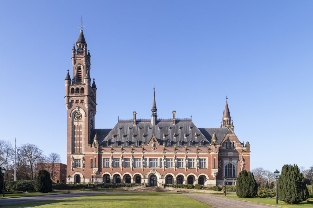 Das Vredespaleis in Den Haag steht in einem Park vor blauem Himmel.