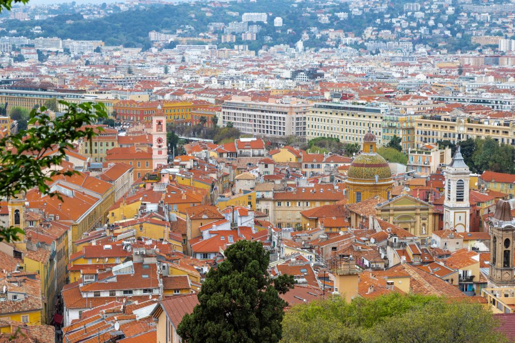Panorama der Altstadt von Nizza mit orangefarbenen Dächern, Kirchtürmen und Hügeln im Hintergrund an der Côte d’Azur.