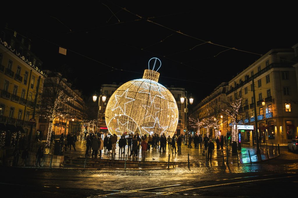 In der Innenstadt von Lissabon steht nachts eine riesige leuchtende Weihnachtskugel auf einem Platz.