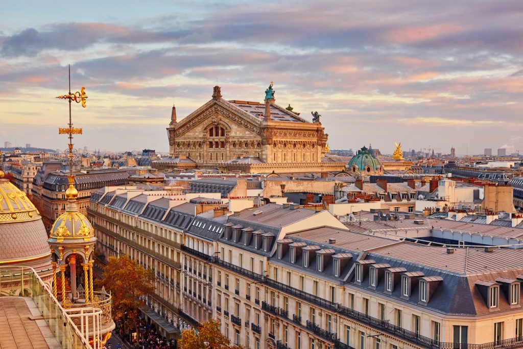 Panorama über die Pariser Dächer mit der Opéra Garnier im warmen Abendlicht.
