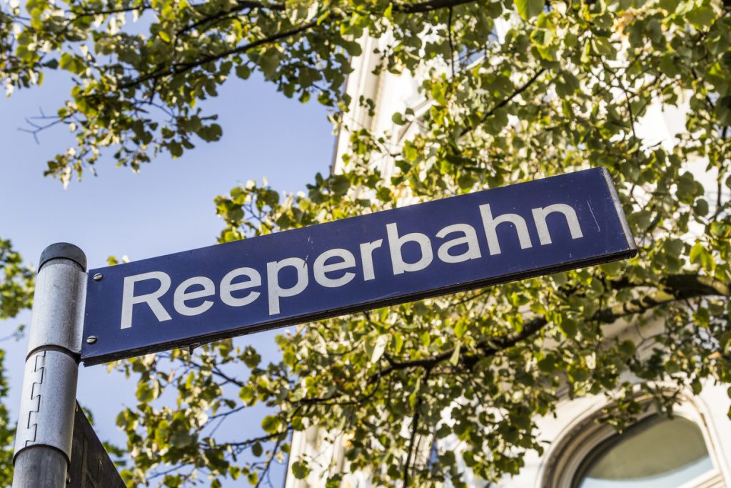 Ein Straßenschild mit der Aufschrift Reeperbahn steht in Hamburg vor blauem Himmel.