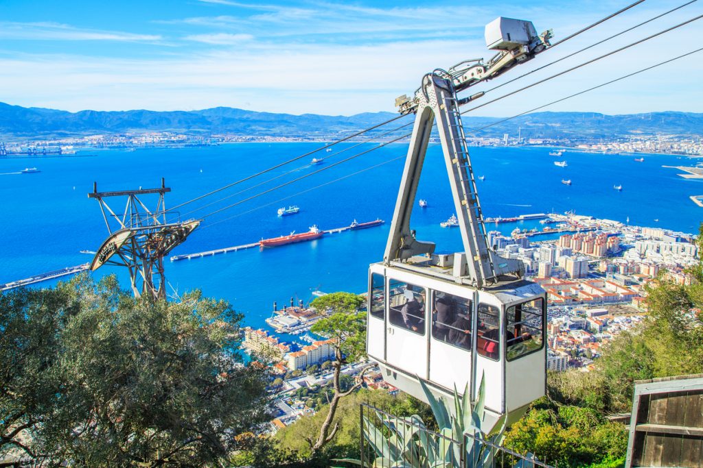 Seilbahnkabine fährt den Felsen von Gibraltar hinauf und gibt den Blick auf Hafen und Meer frei.