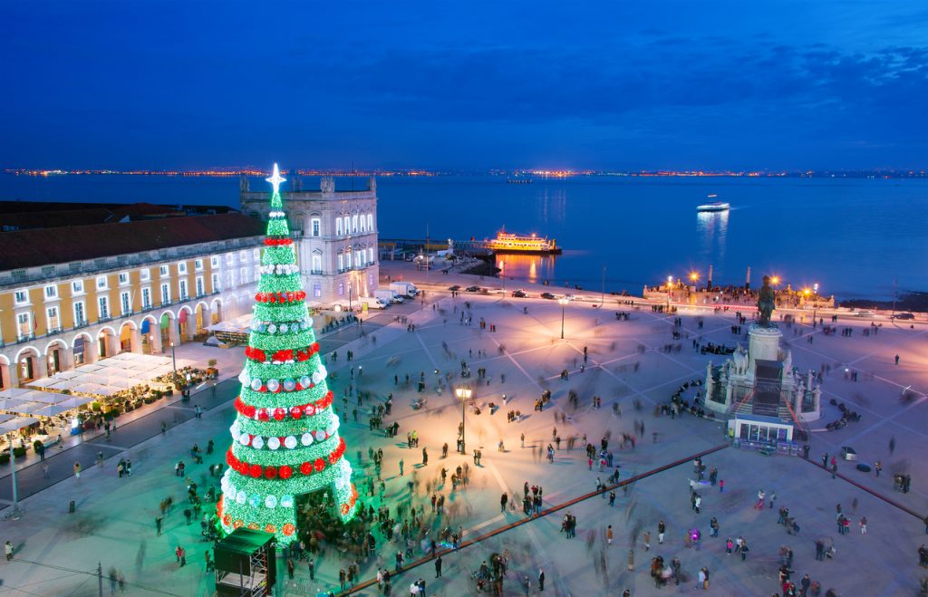 Auf der Praça do Comércio in Lissabon steht ein großer beleuchteter Weihnachtsbaum mit Blick auf den Tejo.